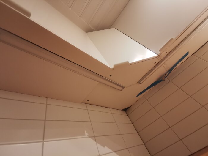 Bild av köksskåp och fläkt mot en kaklad vägg, tagen i uppåtvinklad vy.