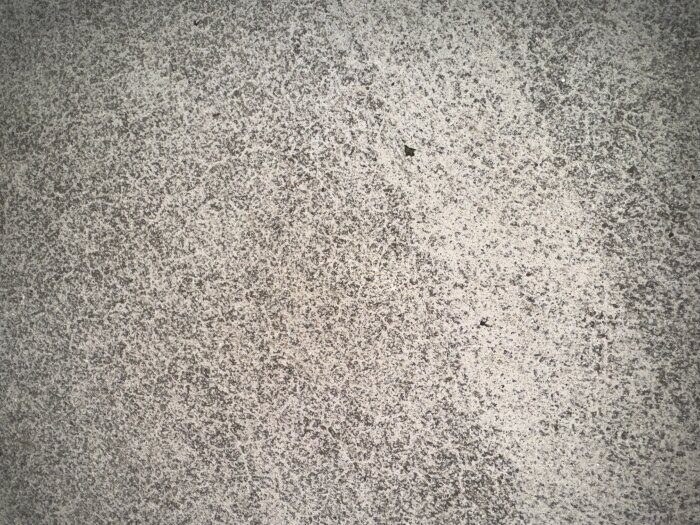 Grå betongyta med ojämn textur och fina små sprickor eller fläckar.