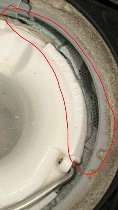 En närbild av en tvättmaskins trumma med smuts och avlagringar längs gummitätningen.