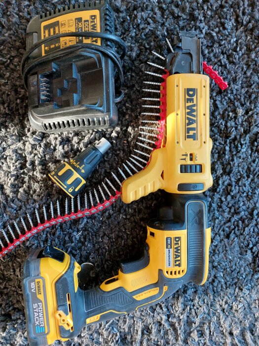 DeWalt elektrisk skruvdragare, batterier, laddare, och borrbitar på en grå textilmatta.