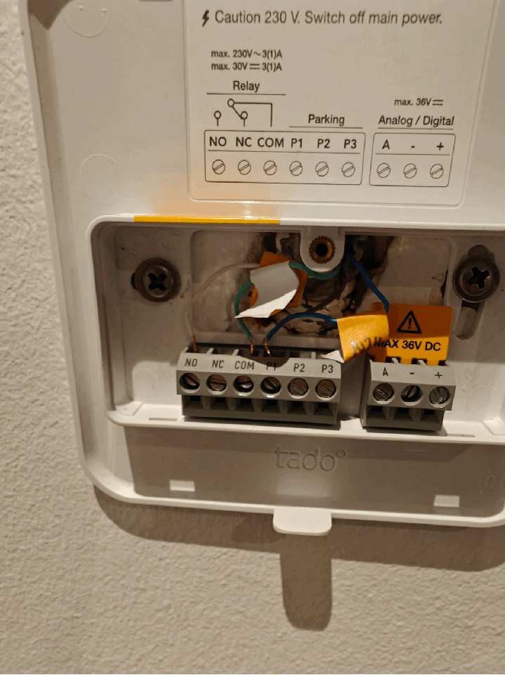 Öppen termostatinstallation; varningsmärken för elektricitet; oanslutna kablar; instruktionsetikett.