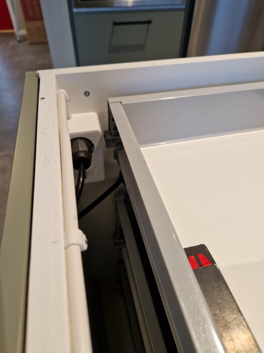 Delvis öppen diskmaskin med synliga gångjärn och frontpanel mot en köksbakgrund.
