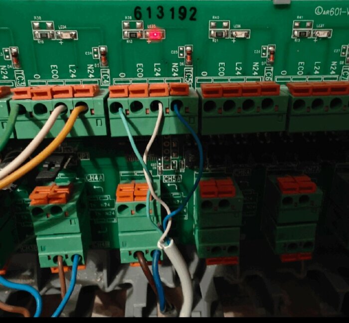 Industriell kretskortsmodul med anslutna kablar och blinkande röda lysdioder. Etikett nummer 613192 synlig.