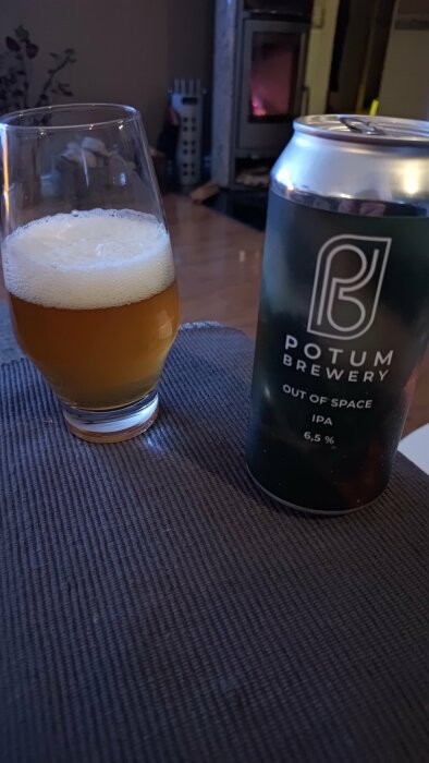 Ett glas öl och en burk IPA från Potum Brewery framför en tänd kamin.