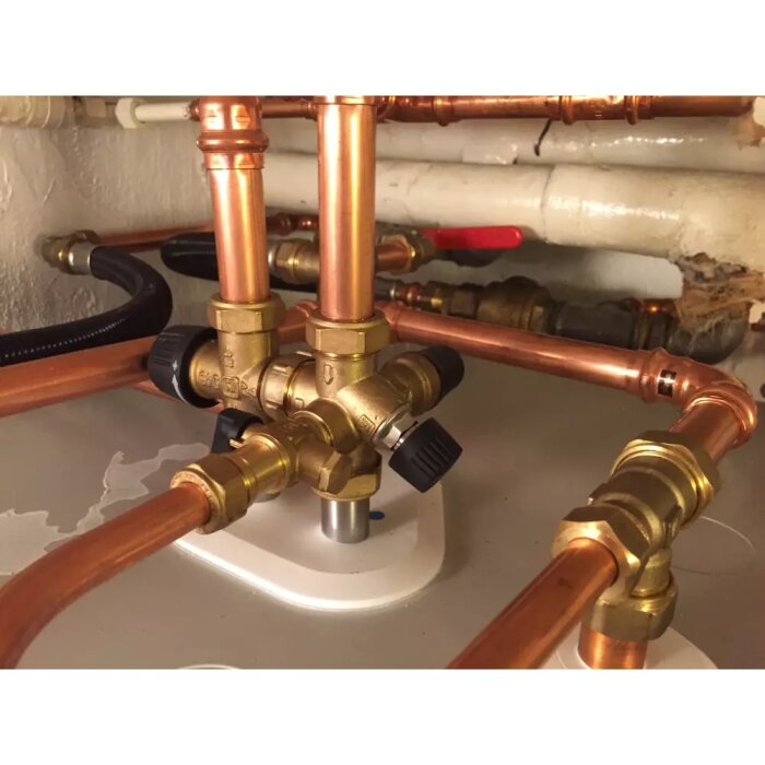 Ett komplext system av kopparör och mässingsventiler med vred för värmesystem eller VVS-installation.