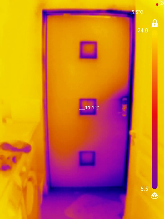 Termisk bildvisning av en dörr, temperaturmätningar synliga, varmare områden i gult, kallare i lila.