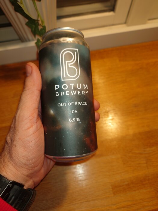 Hand håller burk från Potum Brewery, "Out of Space" IPA-öl, alkoholhalt 6,5%, rymdtema.