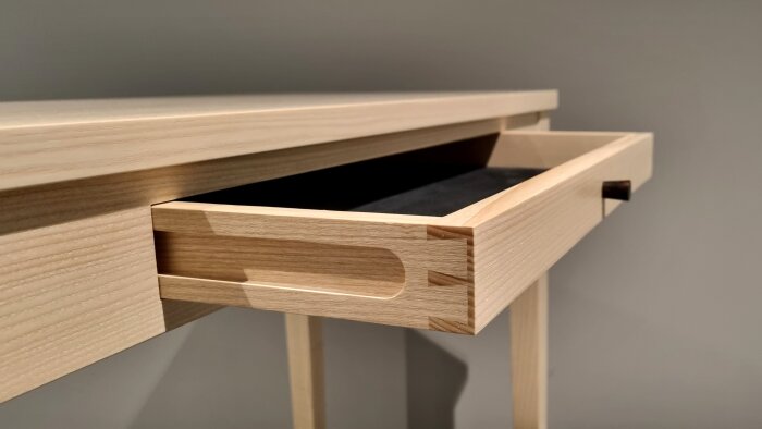 Öppen låda av trä i minimalistisk stil med synliga hantverksdetaljer och mörk inredning.