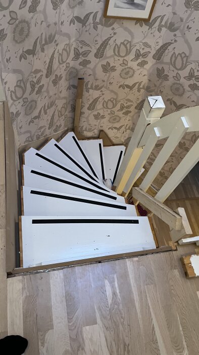 Trappa i hus med vita steg som ligger demonterade på golvet.