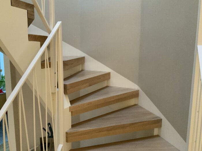 Trätrapp med vit räcke, inomhus, modern stil, neutrala färger, delvis synlig hall nertill.