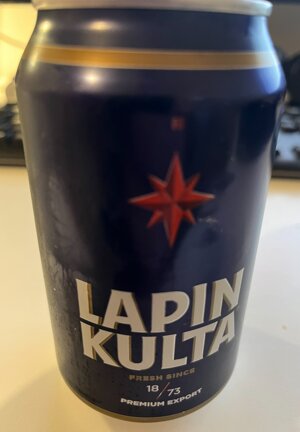 En ölburk märkt "Lapin Kulta", blå bakgrund, röd stjärna, premium export, vitt och guld text, inomhusbelysning.