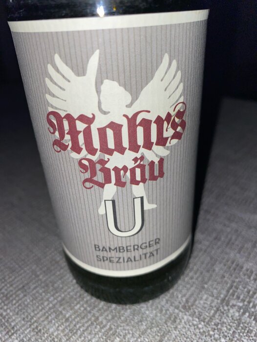 Etikett för "Mahrs Bräu", Bambergerspezialität, ölflaska med vita och röda detaljer på grå botten.