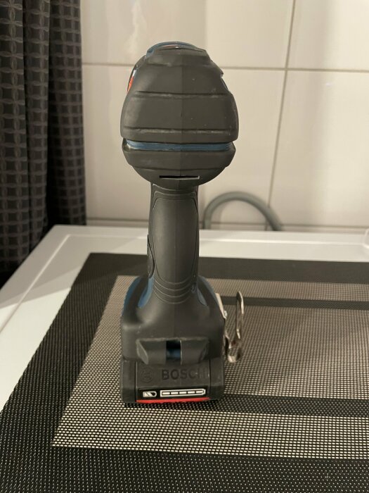 Bosch verktyg på en vävd matta, inomhus, köksmiljö, kakelvägg, modernt och praktiskt.