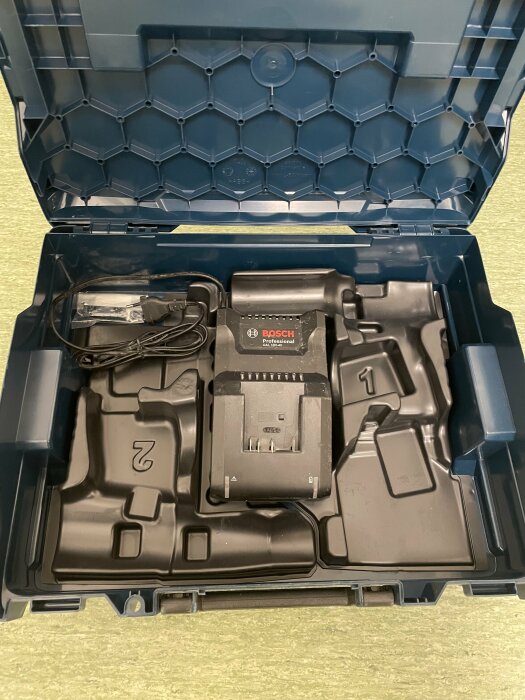 Ett öppet blått Bosch verktygsväska med laddare och tomma fack för ytterligare verktyg och batterier.