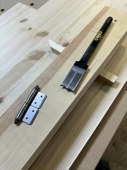 Träplankor, en dörrgångjärn, kniv för träarbete, små träbitar, märkning för hantverk.