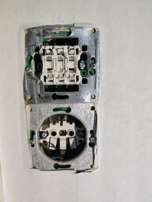 Eluttag utan frontplatta, osäkrat, elektriska komponenter synliga, installation pågår eller reparation, vägg inuti bostad.
