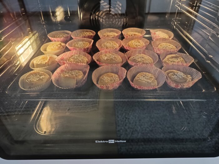 Muffins med sesamfrön bakas i ugn, i rosa och gula formar.