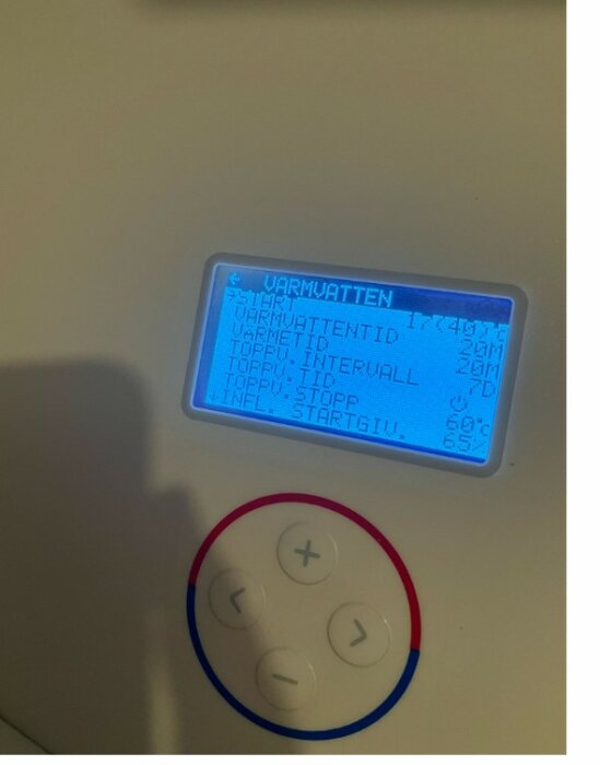 Digital termostat med blå bakgrundsbelysning; visar inställningar för 'VARMVATTEN'; röd och blå knappar nedanför.