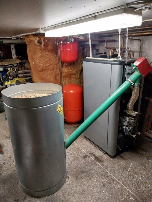 Pelletsbrännare med matarskruv i källare, vedpanna, ackumulatortank, fläkt, isolering. Teknisk utrustning för uppvärmning.