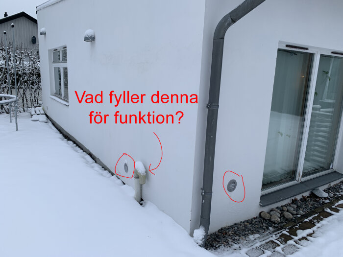 Vinter, snö, husfasad, två ventilationsgaller, frågetext "Vad fyller denna för funktion?".