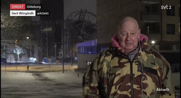 Man i kamouflagejacka med rosa foder, hörlurar, vinter, kväll, Göteborg, utomhus, TV-intervju, berg-och-dalbana i bakgrunden.