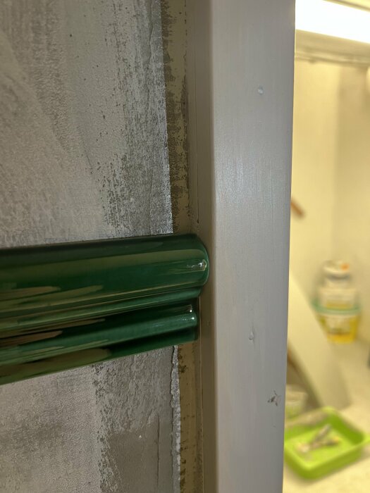 Grön glashylla, vit dörrkarm, ofärdig vägg, inomhus, byggarbetsplats eller renovering pågår.