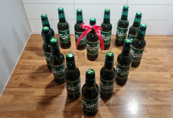 Flaskor ordnade i ett hjärtformat mönster på ett golv, en har ett rött band.