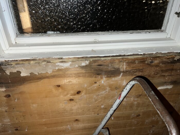 Fönster med kondens, skadad fönsterkarm och fönsterbräda, del av stege, natt, bristfälligt underhåll, renoveringsbehov.