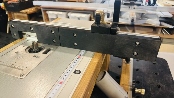 Routerbord med fästande jig och inläggningsguide för träbearbetning. Precision och verktyg synligt.