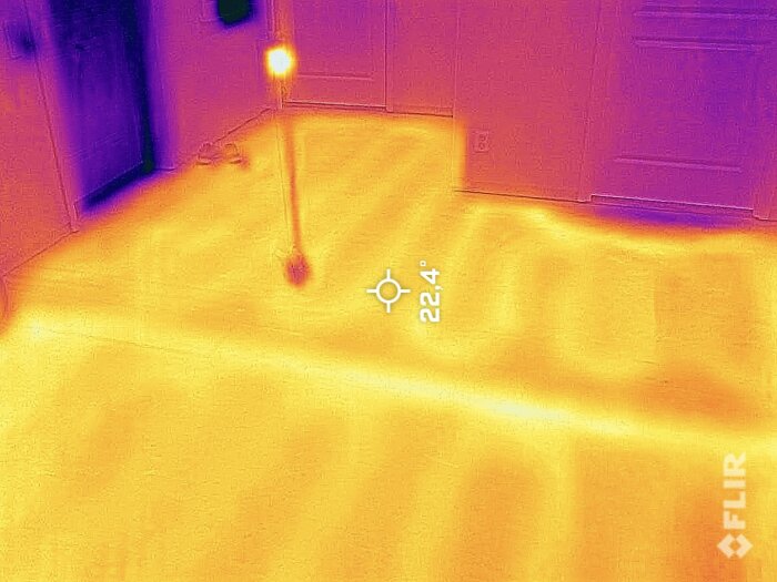 Termisk bild av ett rum, varmare områden är gulaktiga, svalare är lila, 22.4°C visat, ingen person synlig.