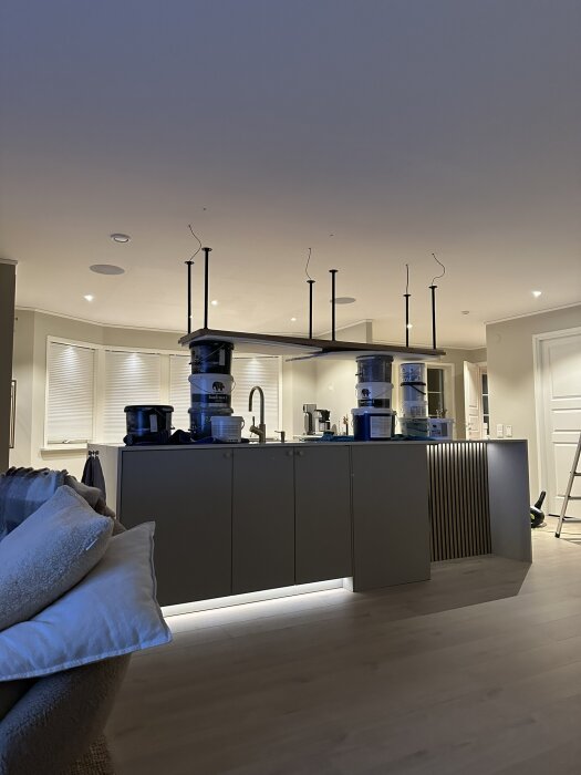 Modernt kök, öppen planlösning, köksö, inbyggd belysning, minimalistisk stil, trägolv, vitt och grått färgschema.