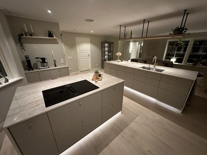 Modernt kök, vita skåp, marmorbänkskiva, inbyggda apparater, trägolv, elegant belysning, minimalistisk design.