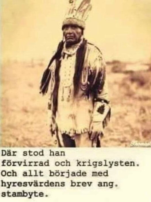 Äldre bild, person i ursprungsamerikansk dräkt, seriöst ansiktsuttryck, ökenliknande bakgrund, sepia toner.