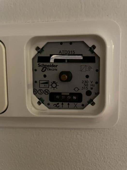Öppen Schneider Electric termostat utan sitt främre skyddslock på en vägg.