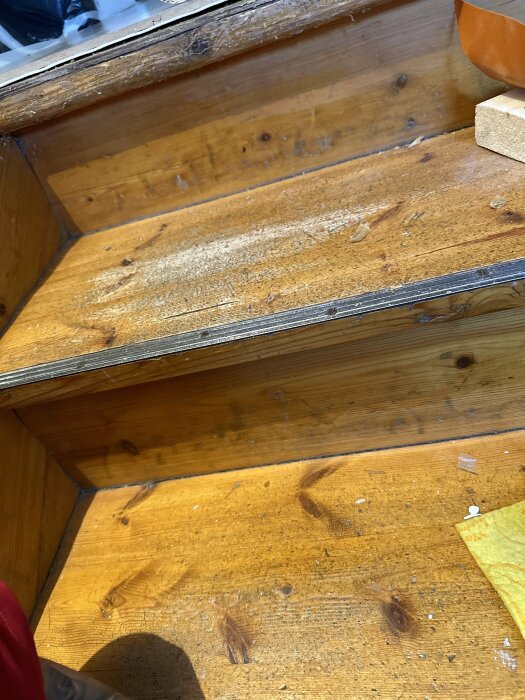 Trätrappa täckt med sågspån och damm, indikerar pågående arbete eller renovering.