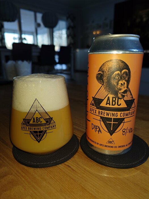 Öl i glas med skum, burk med apa, Apex Brewing Company logotyp, inomhusmiljö, mysig atmosfär.