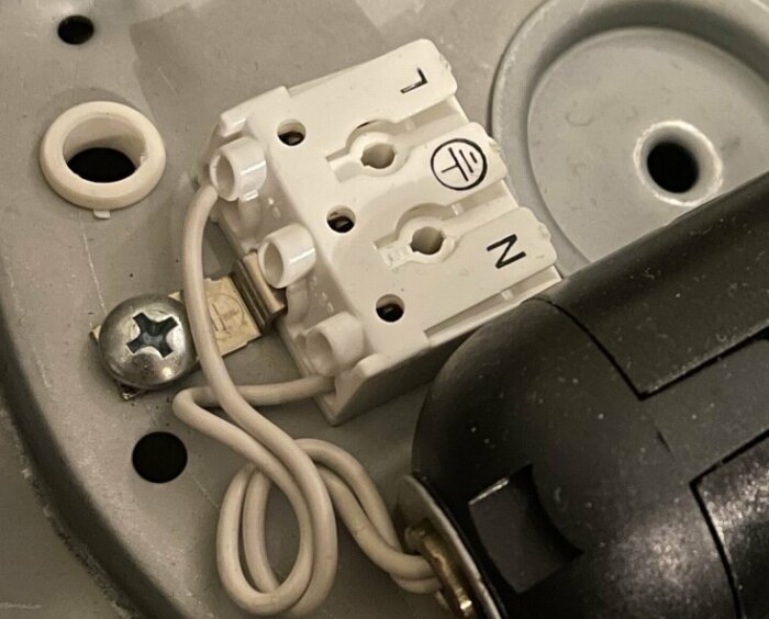 Närbild på öppen elektrisk koppling med kablar och delvis synlig elkontakt.