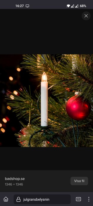 Julgransljus och röd julgranskula i mörk miljö, granbarr i bakgrunden, festlig juldekoration.