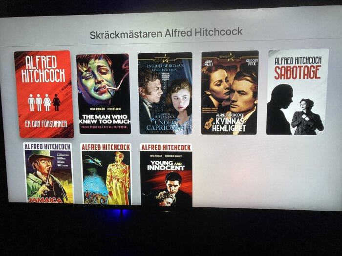 En samling Alfred Hitchcock-filmomslag visas på en skärm. Klassiska thrillers. Text: "Skräckmästaren Alfred Hitchcock."