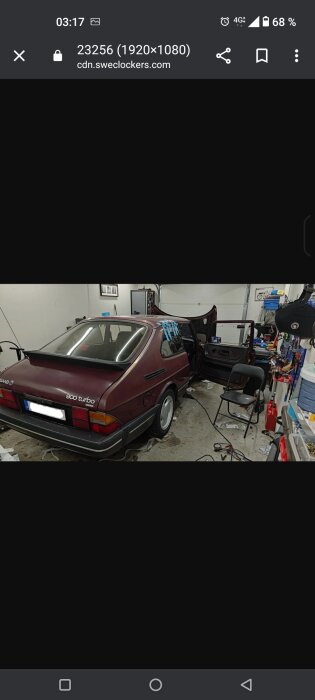 Röd Saab 900 Turbo i en verkstad, öppna dörrar, verktyg och utrustning runtomkring.