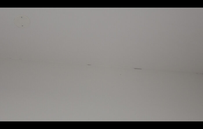 Vit yta med linjer, skuggor, rund föremål högst upp.