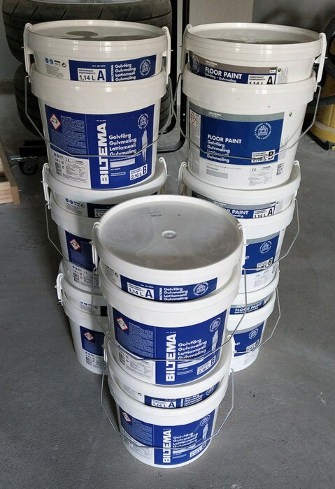 Staplar av vita färgburkar märkta "Floor Paint" i en förvaring.