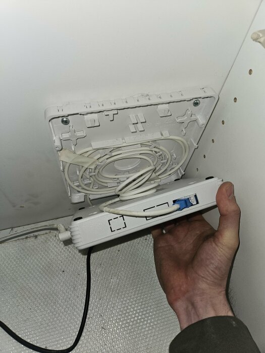 Installation eller reparation av en kabelansluten enhet, förmodligen en router, på en vägg.