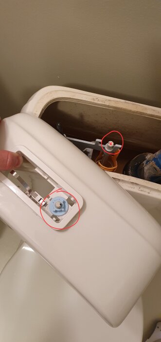Inuti en toalettcistern; hand öppnar locket, flottörventil och påfyllningsventil synliga, behöver rengöras.