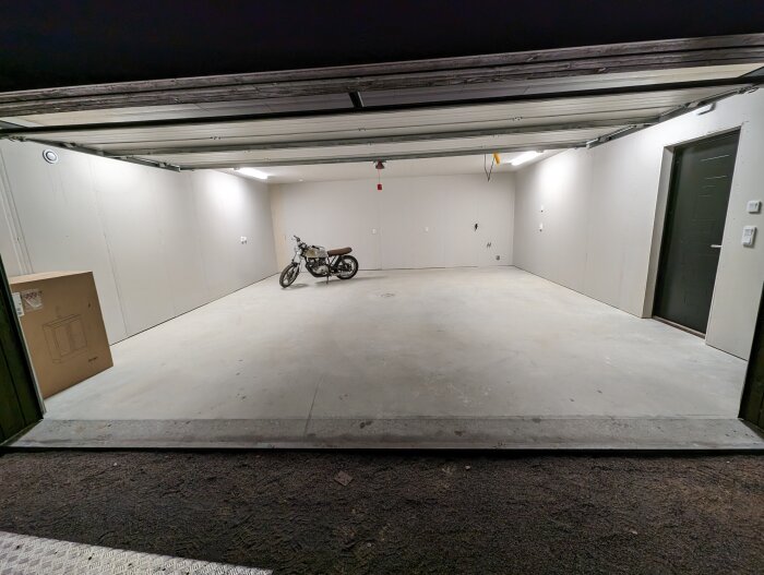 Tom garage med öppen dörr, en motorcykel, betonggolv, vita väggar, belysning, dörr bakom.