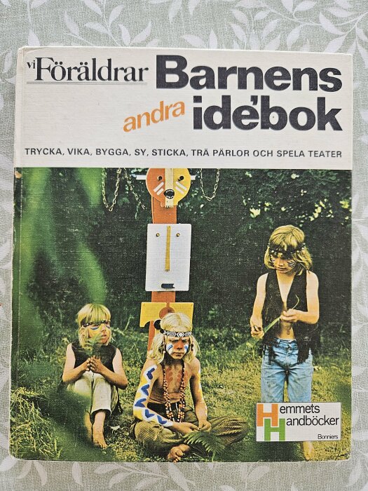 Svensk bok för barnaktiviteter; barn klädda i kreativa dräkter leker utomhus.