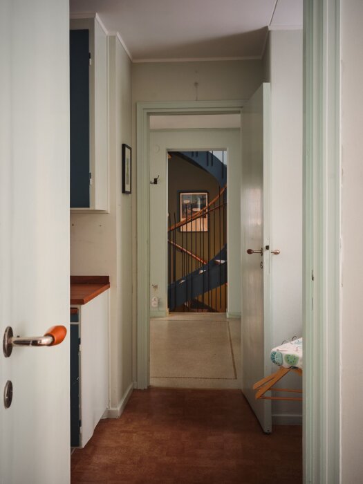 Korridor i hemmiljö med synliga dörrar, trapphus i bakgrund, neutral färgpalett, bostadsinredning, ingen människa synlig.