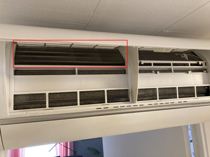 Öppnad luftkonditioneringsenhet visar filter, behöver rengöring, monterad på vägg, interiör.