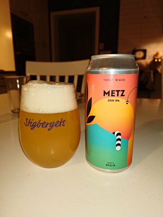 Ölglas fyllt med skummande öl bredvid en färgglad burk med texten "METZ DDH IPA".