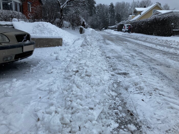 Snötäckt gata, bil, plogad snö, bostadshus, vinterdag, kallt väder, bilar parkerade, snöig förort.